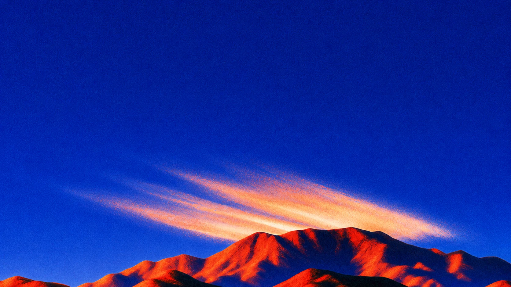 Chaîne de montagnes embrasée au crépuscule sous un ciel bleu profond : le moment où le relief se dessine